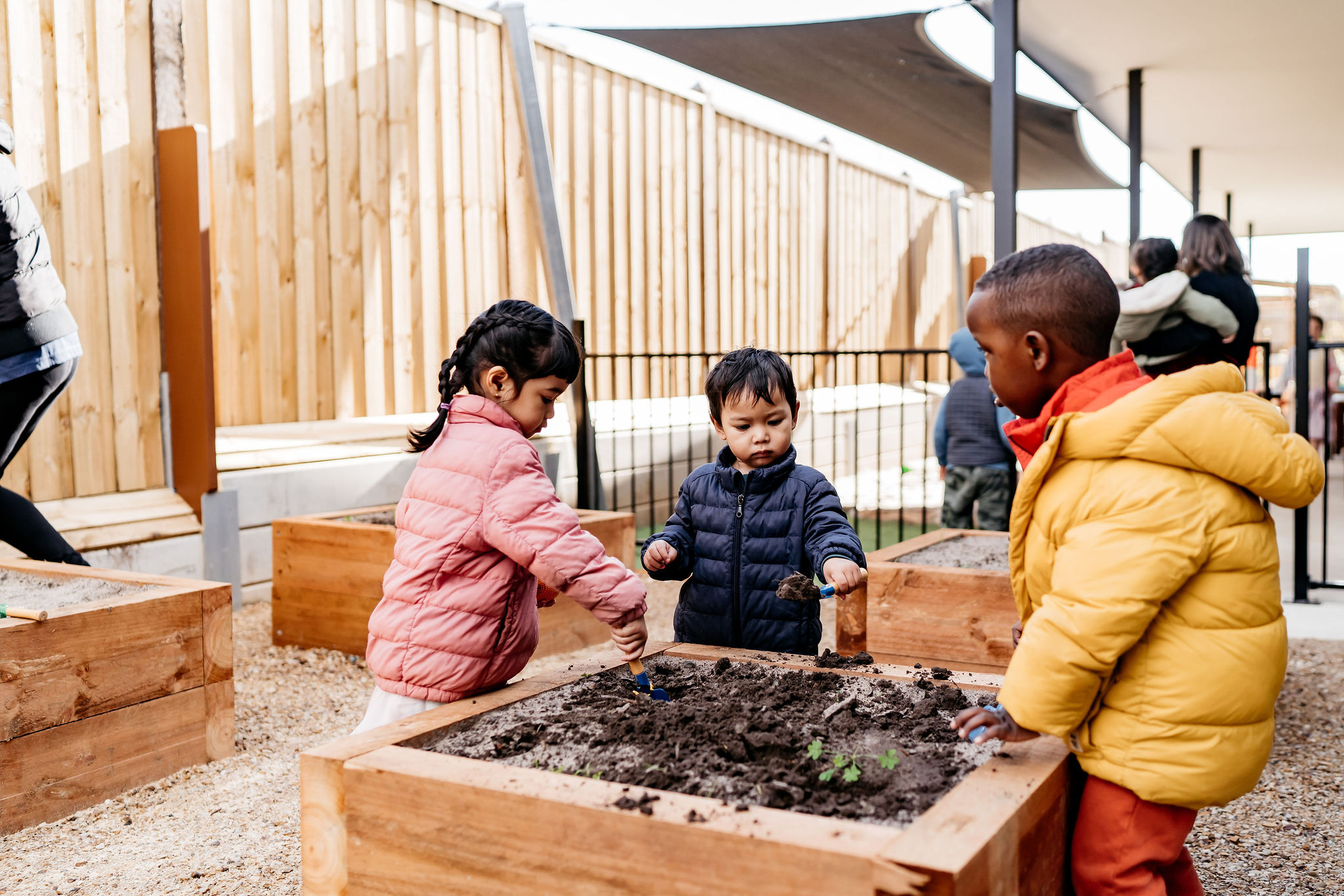 3 kids at Child's Play Early Learning Centre playing and learning in the veggie garden area